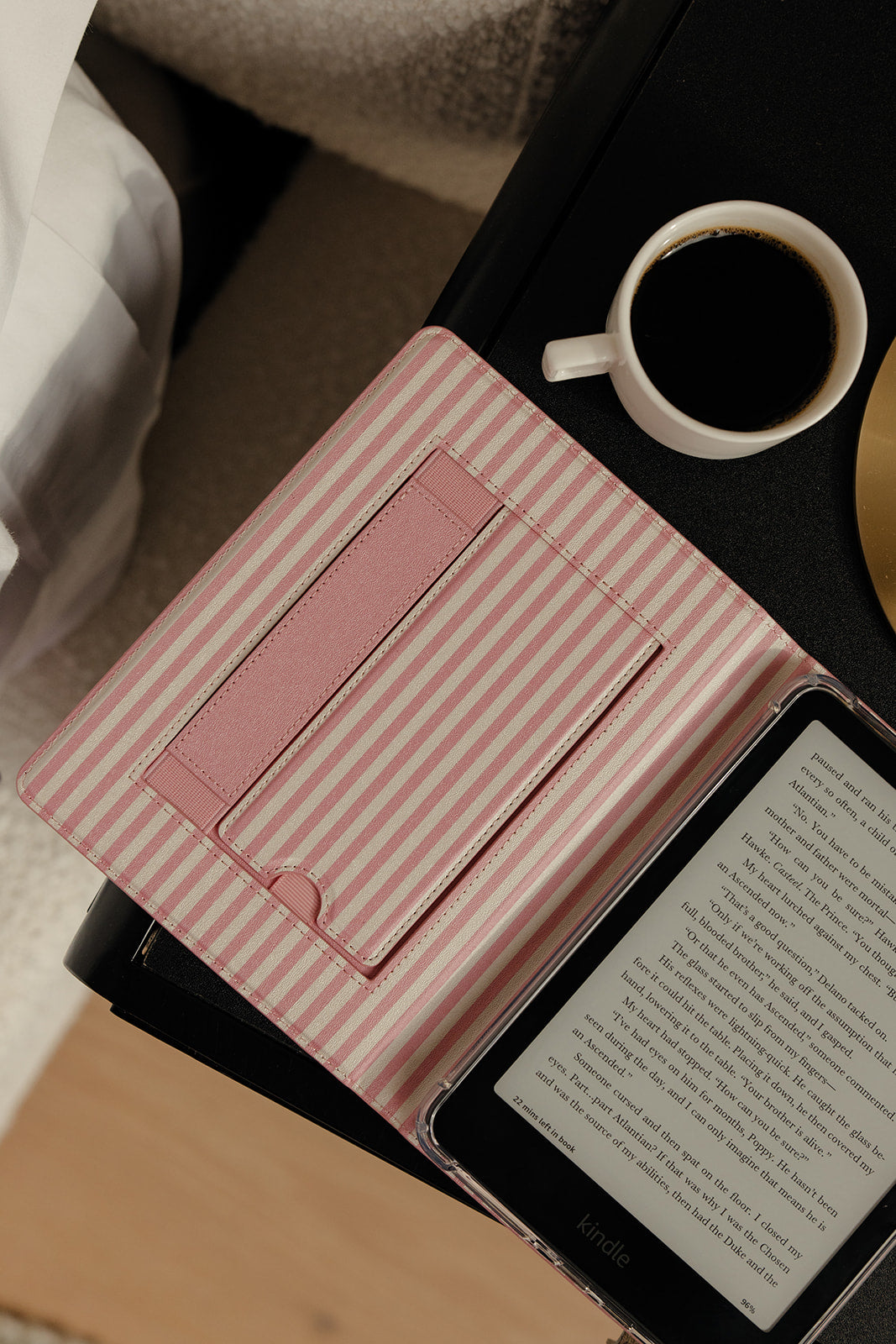 Inside of case with pink stripes sitting on a table with a cup of coffee in the background
